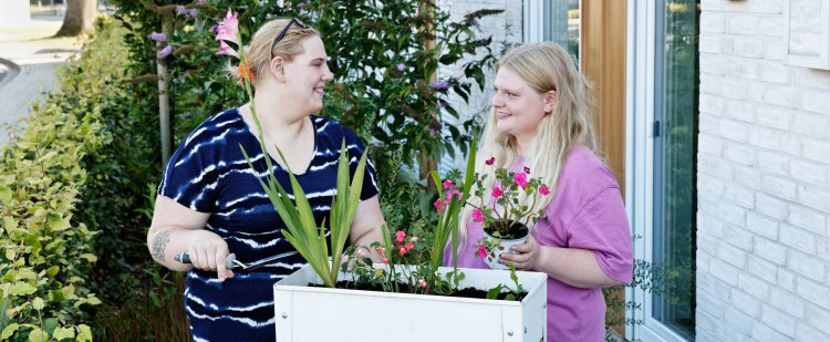 Zwei Frauen pflegen Blumen auf der Terrasse.