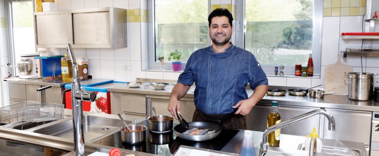 Koch brät Garnelen in der Pfanne.