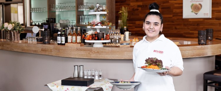 Mitarbeiterin serviert Essen im Restaurant.