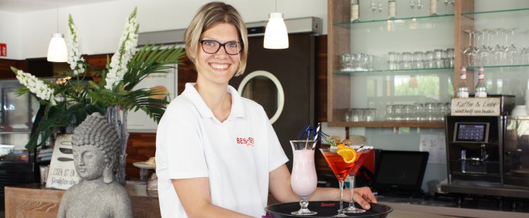 Eine junge Frau trägt Cocktails auf einem Tablett.