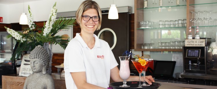 Eine junge Frau trägt Cocktails auf einem Tablett.