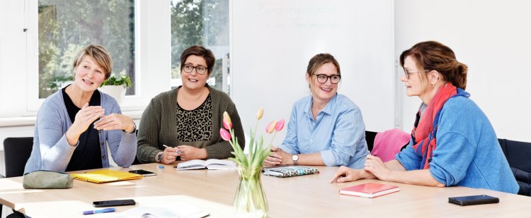 Vier Mitarbeiterinnen sitzen in einer Teambesprechung.