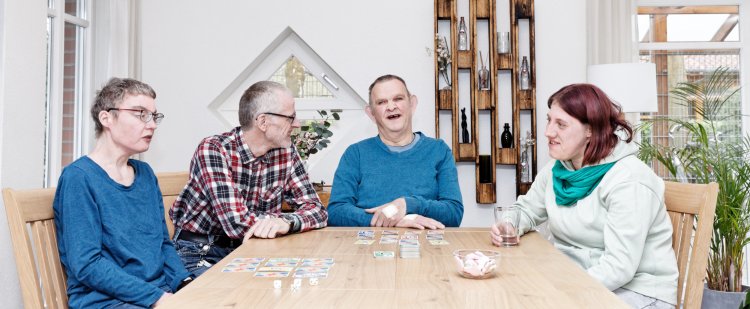 Vier Bewohnerinnen und Bewohner beim Gesellschaftsspiel.