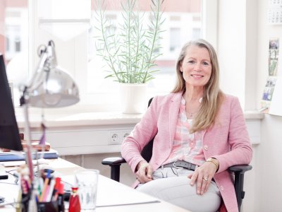 Weibliche Leitungskraft sitzt im Büro am Schreibtisch.