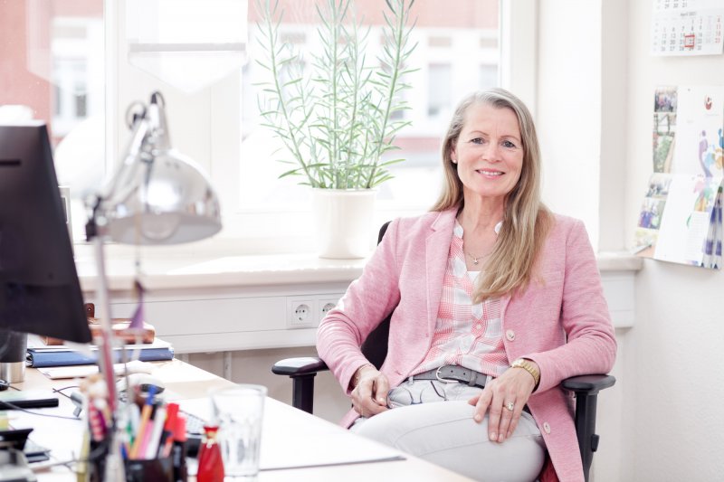 Weibliche Leitungskraft sitzt im Büro am Schreibtisch.