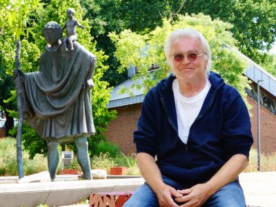 Mann sitzt draußen vor Christophorus-Statur.