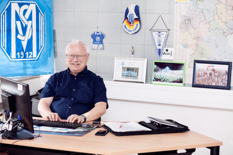 Integrationsbegleiter sitzt im Büro am Schreibtisch und tippt am Computer.