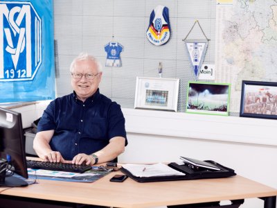 Integrationsbegleiter sitzt im Büro am Schreibtisch und tippt am Computer.