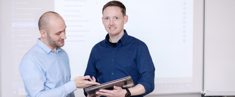 IT-Fachinformatiker zeigt seinem Kollegen etwas auf Tablet.