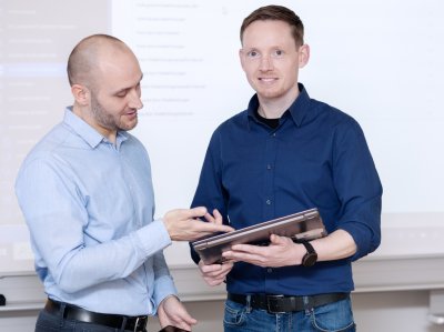 IT-Fachinformatiker zeigt seinem Kollegen etwas auf Tablet.