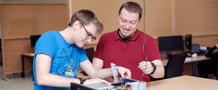 Fachinformatiker und Beschäftigter schrauben an einem ausgebauten Computerlaufwerk.