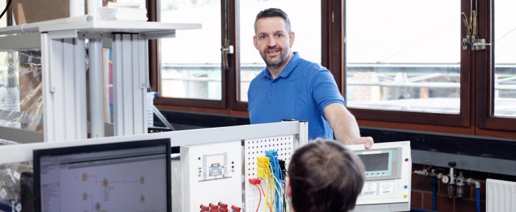Elektrotechniker und Beschäftigter an einer Maschine in der Werkstatt.