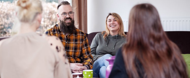 Erzieherin und Erzieher auf Sofa im Gespräch mit zwei Klientinnen.
