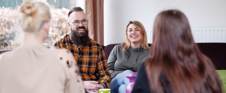 Erzieherin und Erzieher auf Sofa im Gespräch mit zwei Klientinnen.