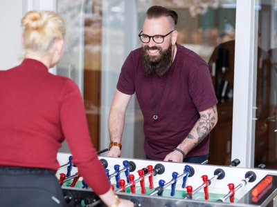 Erzieher und Klientin spielen Tischkicker gegeneinander.