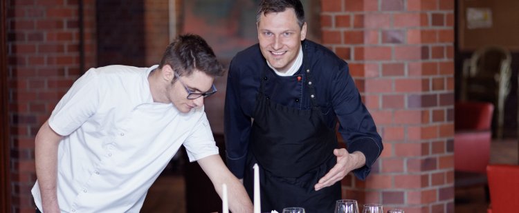 Küchenmeister und Beschäftigter decken Tisch im Restaurant.
