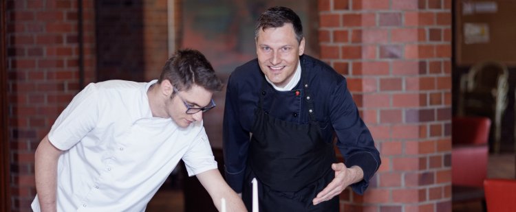 Küchenmeister und Beschäftigter decken Tisch im Restaurant.
