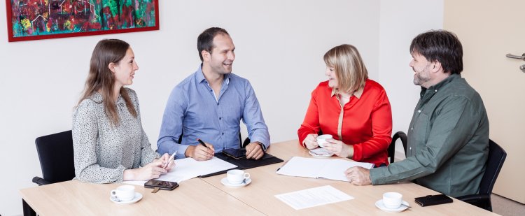 Gruppe aus Fachkräften im Gespräch am Tisch.
