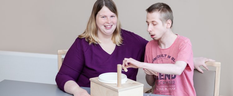 Heilerziehungspflegerin und Klient trainieren die Motorik mit kleinen Gegenständen aus Metall und Holz.