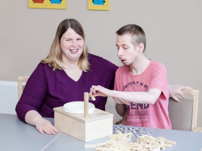 Heilerziehungspflegerin und Klient trainieren die Motorik mit kleinen Gegenständen aus Metall und Holz.