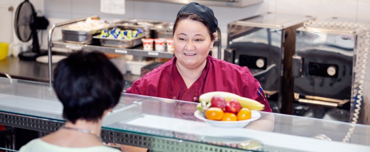 Servicekraft bedient Frau in der Großküche.