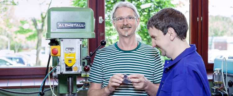 Maschinenbauer und Beschäftigter neben einem Bohrer in der Werkstatt.
