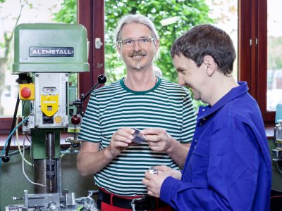 Maschinenbauer und Beschäftigter neben einem Bohrer in der Werkstatt.