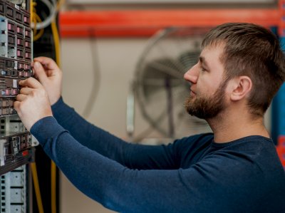 Auszubildener in der Fachinformatik prüft die Schalter in einem Serverschrank.