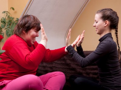 Zwei Frauen sitzen auf einem Sofa und klatschen in die Hände.
