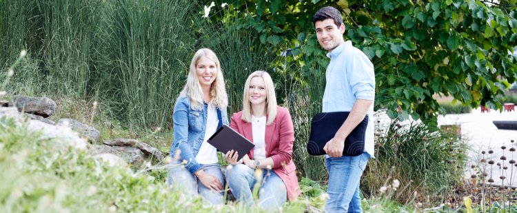 Gruppe aus Nachwuchskräften mit technischen Geräten im Grünen.
