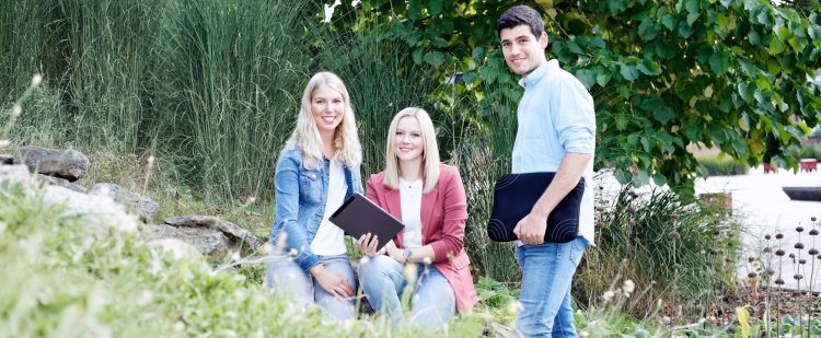 Gruppe aus Nachwuchskräften mit technischen Geräten im Grünen.