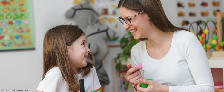 Praktikantin und Mädchen spielen im Kindergarten mit Holzspielzeug.